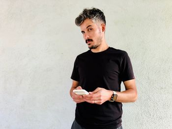 Portrait of young man standing against white background