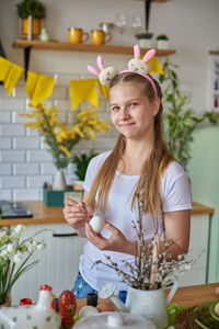 Portrait of smiling girl holding egg and paintbrush