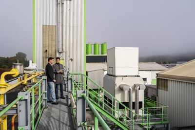 Mature businessman with colleague discussing together at recycling plant