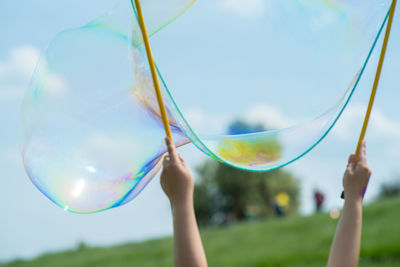 Cropped hands of girl holding bubble wand on land