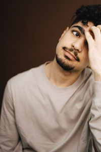 Tired man with head in hand against brown background