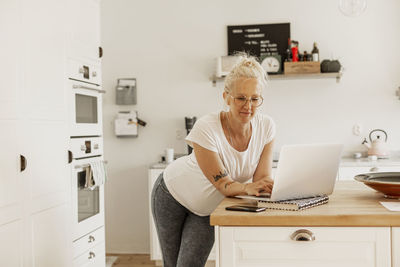 Woman using laptop in kitchen