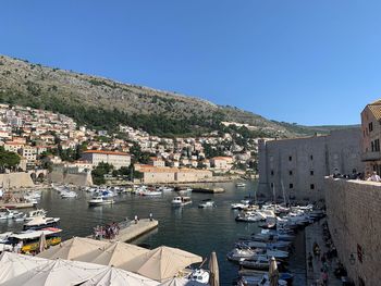 High angle view of townscape by sea against clear blue sky