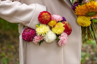 A bouquet of autumn flowers in the pocket of a beige coat