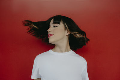 Portrait of beautiful young woman against red wall