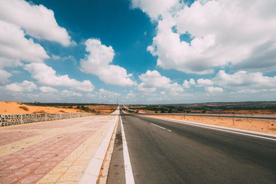 Empty road along countryside landscape against sky