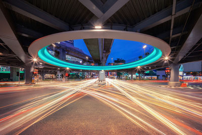 Light trails on multiple lane highway below elevated road in city at night