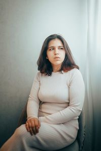 Portrait of young woman standing against wall