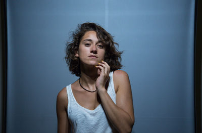 Portrait of young woman standing against gray backdrop