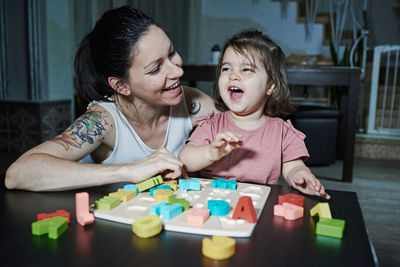 A mother teaching her daughter the letters of the alphabet. concept of learning