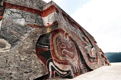 Low angle view of carvings on wall against sky