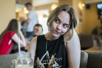 Woman making face while sitting in restaurant