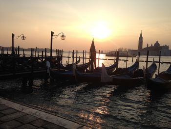 Boats moored in sea at sunset