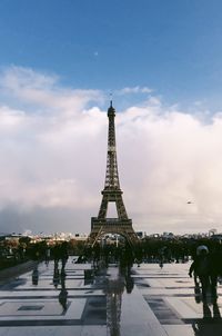 Communications tower in city against cloudy sky