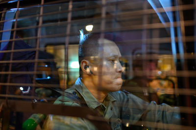 Portrait of young man looking through glass window