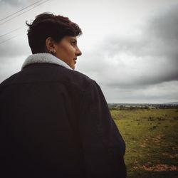 Rear view of man looking away on field against sky