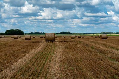 Hay bales on field against sky