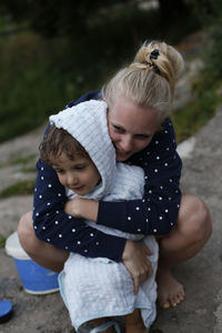 A young adult woman hugs a young boy after swimming