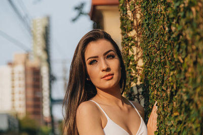 Close-up of beautiful woman standing against creeper wall