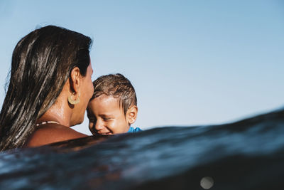 Intimate portrait of mother and son playing at sea