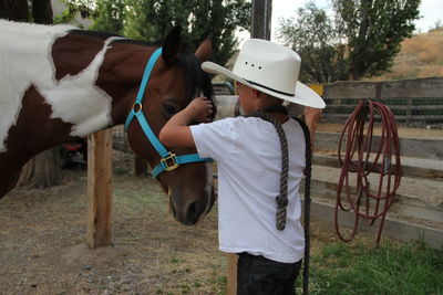 Side view of boy petting horse