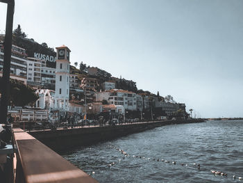 Buildings by sea against clear sky