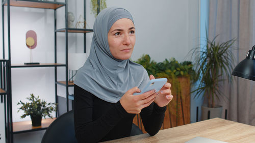 Young woman using mobile phone while sitting at home