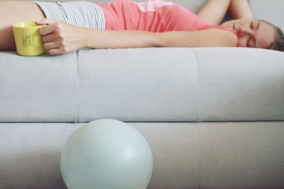 Midsection of woman sitting on sofa at home