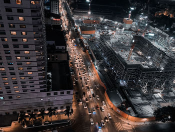 High angle view of illuminated city street amidst buildings at night