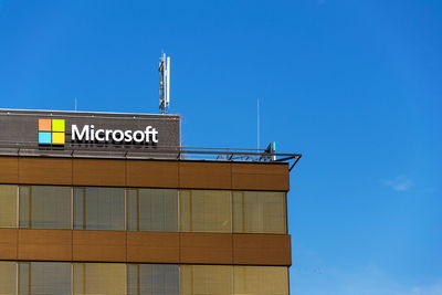 Low angle view of text on building against clear blue sky