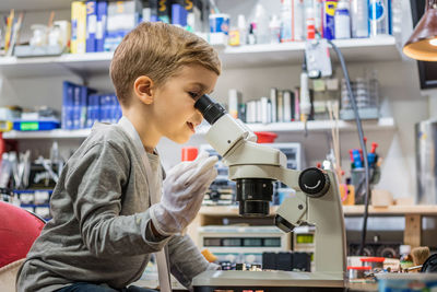 Boy repairing computer part on table at home