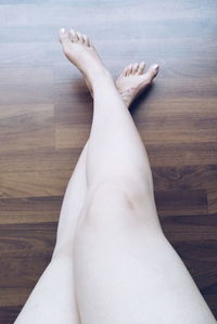 Low section of woman lying on hardwood floor