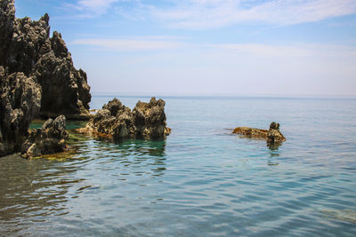 View of rocks in sea against sky