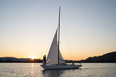 Sailboat sailing on sea against clear sky during sunset