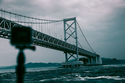 Low angle view of bridge against cloudy sky