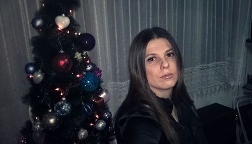 Portrait of woman with christmas tree at home