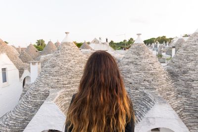 Rear view of woman against trulli houses at alberobello