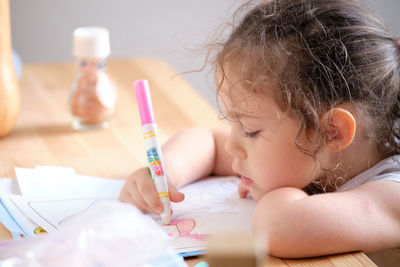 Little girl playing with invisible ink and coloring book