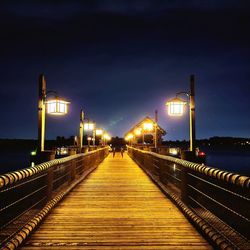 Illuminated bridge over calm river at night