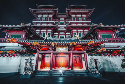 Man sitting against buddhist temple at night