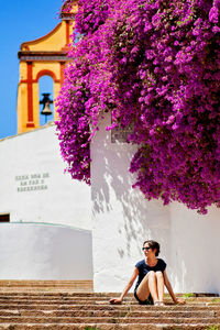 Portrait of woman with pink flowers against built structure