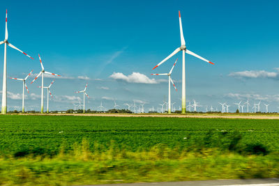 Windmills on field against sky