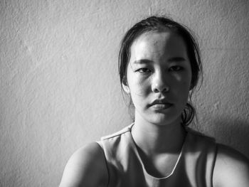 Close-up portrait of a young woman against wall