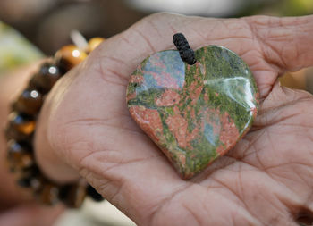 Close-up of hand holding heart shape pendant