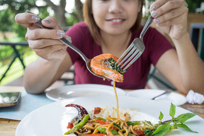 Close-up of woman eating food on table at restaurant