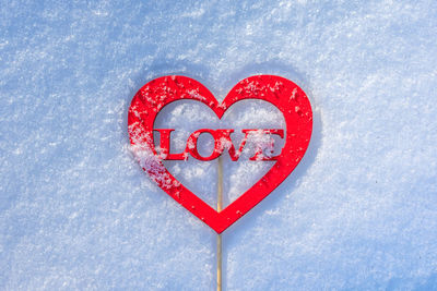 A heart-shaped figure with the word love lies on the snow. love message in romantic form