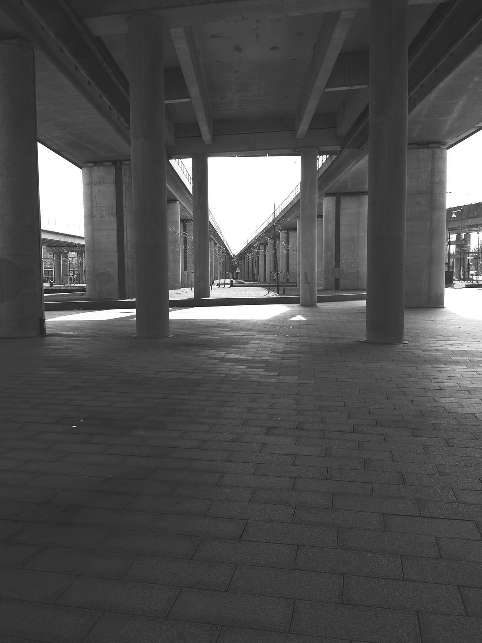 architecture, built structure, architectural column, column, bridge - man made structure, indoors, connection, support, sunlight, below, the way forward, diminishing perspective, engineering, bridge, transportation, colonnade, shadow, sky, pillar, day