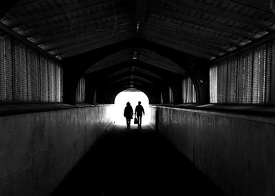 Rear view of people walking in tunnel