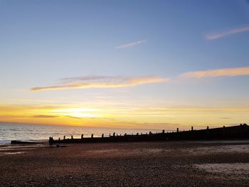 Silhouette on beach against sky during sunset