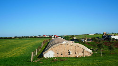Built structure on field against clear blue sky